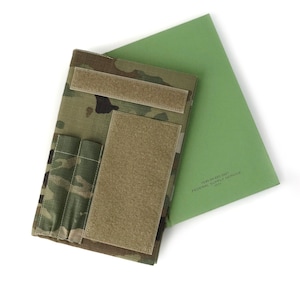 May include: A camouflage-patterned tactical notebook cover with hook and loop closures and pockets, paired with a green document. The document has the text "FEDERAL SUPPLY SERVICE".