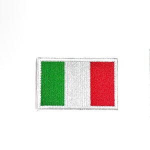 May include: A rectangular patch featuring the Italian flag. The flag design includes vertical stripes of green, white, and red. The patch has a silver border and is likely for clothing or accessories.