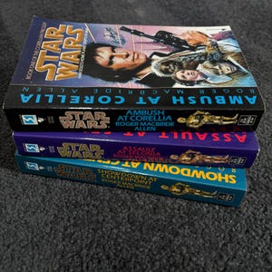以下が含まれることがあります： 3冊のスターウォーズ小説が積み重ねられています。一番上の本は「Ambush at Corellia」で、ハン・ソロが表紙に描かれています。他の2冊は「Assault at Selonia」と「Showdown at Centerpoint」です。