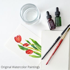 May include: A watercolor painting of red tulips on a white card with two bottles of paint, two paintbrushes, and a glass of water.