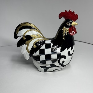 May include: A decorative rooster figurine with a red comb and beak, black and white checkered body, and gold and white accents. The figurine has a detailed design and is likely made of ceramic or a similar material.