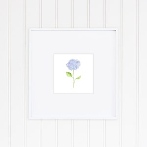 May include: A framed watercolor painting of a single blue hydrangea flower with green leaves on a white background.