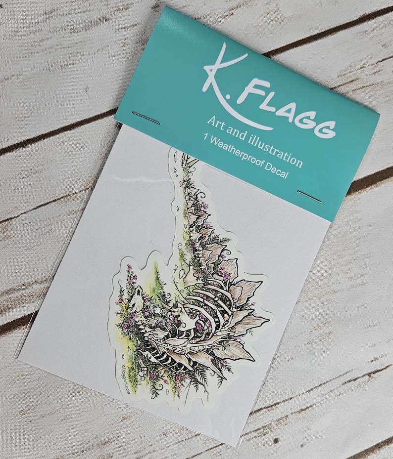 Pode incluir: Um decalque &agrave; prova de intemp&eacute;ries com uma ilustra&ccedil;&atilde;o detalhada de um esqueleto rodeado de flores roxas e folhagem verde. O decalque &eacute; embalado em um saco de pl&aacute;stico transparente com um cabe&ccedil;alho turquesa que diz "K.FLAGG Art and Illustration 1 Weatherproof Decal".