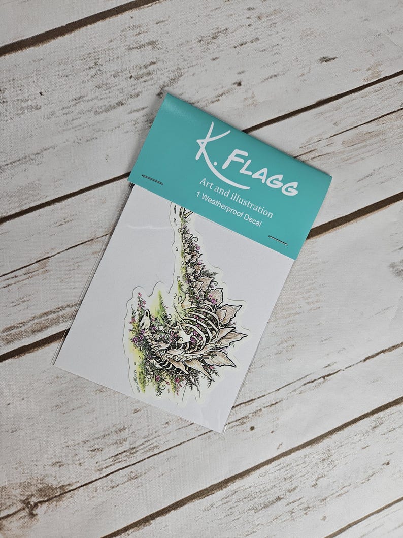 Pode incluir: Um decalque &agrave; prova de intemp&eacute;ries com uma ilustra&ccedil;&atilde;o detalhada de uma criatura esquel&eacute;tica cercada por folhagem e flores. O decalque &eacute; embalado em uma manga de pl&aacute;stico transparente com um cart&atilde;o branco que diz "K. Flagg Art and Illustration 1 Weatherproof Decal".