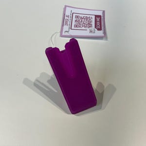 Könnte beinhalten: Ein lilafarbener Reißverschluss-Schieber aus Kunststoff mit einem kleinen rechteckigen Etikett mit der Aufschrift "SCAN ME" und einem QR-Code.