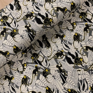 Puede incluir: Tela con un patrón repetido de monos negros con caras y manos amarillas, sobre un fondo de hojas estilizadas blancas, grises y negras. El diseño tiene un tema tropical.