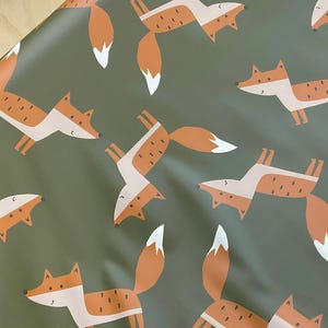 Könnte beinhalten: Geschenkpapier mit einem sich wiederholenden Muster aus stilisierten Füchsen. Die Füchse sind orange mit weißen und beigen Akzenten auf einem gedämpften grünen Hintergrund. Die Füchse sind in verschiedenen Posen, was ein verspieltes Design ergibt.