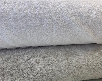 May include: Two towels, one white and one gray, are folded and stacked on top of each other. The towels are made of a soft, fluffy material.