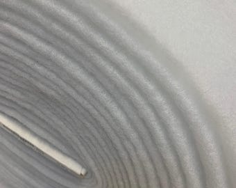 May include: Close-up of a white, rolled-up fabric. The fabric is soft and fluffy, with a slightly textured surface.