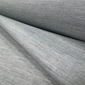 Könnte beinhalten: Nahaufnahme einer Rolle hellgrauen Stoffes. Der Stoff hat ein strukturiertes Aussehen mit sichtbaren gewebten Fäden. Das Material ist gefaltet und zeigt die Schichten und die Textur des Textils. Der Stoff scheint ein mittleres Gewicht zu haben.