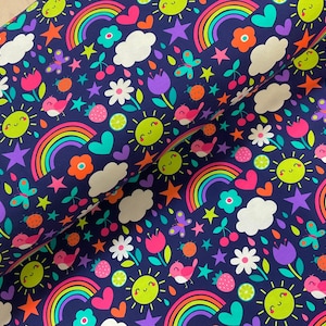 May include: A roll of fabric with a whimsical pattern on a navy blue background. The design features smiling suns, rainbows, clouds, stars, flowers, birds, butterflies, hearts, and strawberries in bright colours.