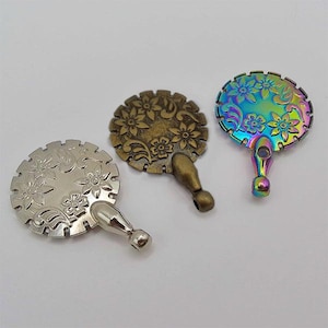 Peut inclure: Trois breloques métalliques décoratives avec des motifs floraux. Les breloques sont en argent, bronze et couleurs irisées. Chaque breloque a une boucle en haut pour l'attacher à un collier, un bracelet ou d'autres bijoux.