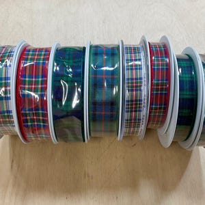 May include: Eight spools of plaid ribbon in various colors, including red, green, and blue. The ribbon is wrapped around white spools.