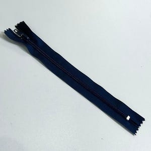 May include: A dark blue zipper with a silver slider. The zipper is about 15 inches long.