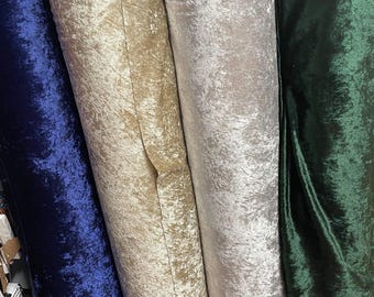 Puede incluir: Primer plano de cuatro rollos de tela de terciopelo arrugado en varios colores. Los colores incluyen azul oscuro, beige, plateado y verde bosque. La tela tiene un aspecto texturizado y brillante.