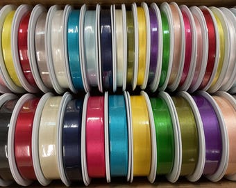 May include: A collection of spools of ribbon in various colors, including red, blue, green, yellow, and white. The ribbon is wound around white spools.