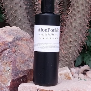 May include: A black bottle of Aloe Pothic aloe vera extract lotion. The bottle is labelled with the product name and ingredients, including aloe vera extract, cetyl alcohol, rice protein, and provitamin B5.