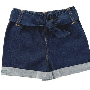 May include: Dark blue denim shorts with a wide, self-tie belt. The shorts have a cuffed hem and are made of a soft, comfortable fabric.