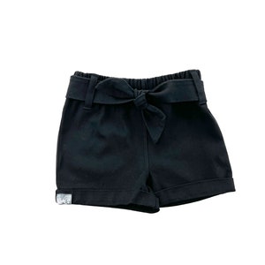 May include: Black cotton shorts with a bow tie detail at the waist.