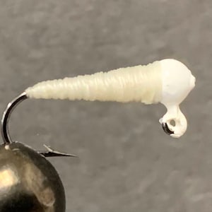 May include: White fly tying material with a small hook attached.