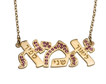 May include: A gold-colored pendant necklace with Hebrew script spelling out a name, accented with small, pink gemstones. The necklace hangs from a delicate chain, creating an elegant and personalized accessory.