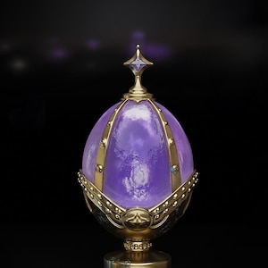 May include: A decorative, egg-shaped object with a purple, translucent center. The object is adorned with gold-colored metal accents, including bands, a base, and a star-shaped finial. The design suggests a fantasy or luxury theme.