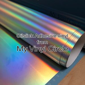 May include: A roll of iridescent oil slick adhesive vinyl from My Vinyl Circle. The vinyl is silver with a rainbow sheen. The text "My Vinyl Circle" and "Oilslick Adhesive vinyl from My Vinyl Circle" is printed on the roll.