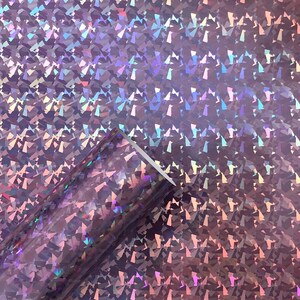 May include: A roll of iridescent holographic vinyl with a pink and purple color scheme. The vinyl has a textured, diamond-like pattern.