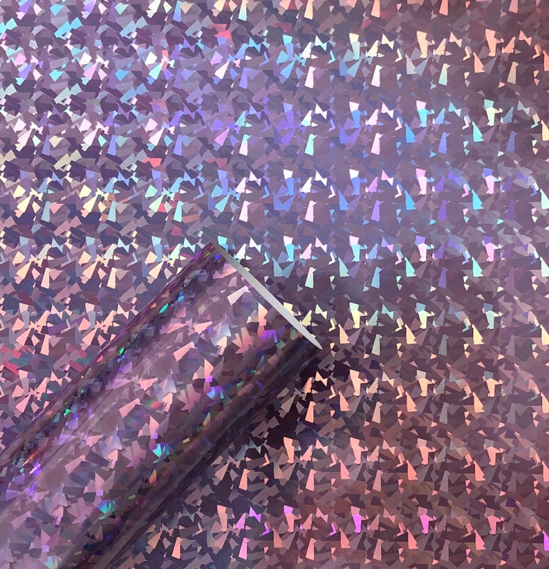 May include: A roll of iridescent holographic vinyl with a pink and purple color scheme. The vinyl has a textured, diamond-like pattern.