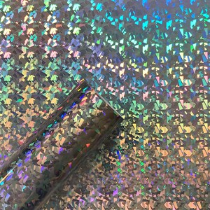 May include: A sheet of iridescent holographic vinyl with a textured, diamond-shaped pattern. The vinyl has a silver base color with a rainbow sheen.