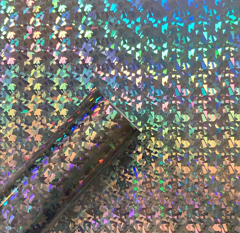 May include: A sheet of iridescent holographic vinyl with a textured, diamond-shaped pattern. The vinyl has a silver base color with a rainbow sheen.