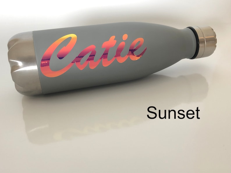 Peut inclure: Bouteille d'eau en acier inoxydable grise avec un autocollant en vinyle couleur coucher de soleil qui dit "Catie".