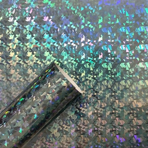 May include: A roll of iridescent holographic vinyl with a textured, diamond-like pattern. The vinyl is a dark gray color with a subtle blue and green shimmer.