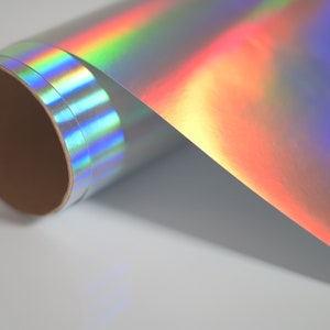May include: A roll of iridescent holographic vinyl with a rainbow sheen. The vinyl is rolled up on a cardboard core.
