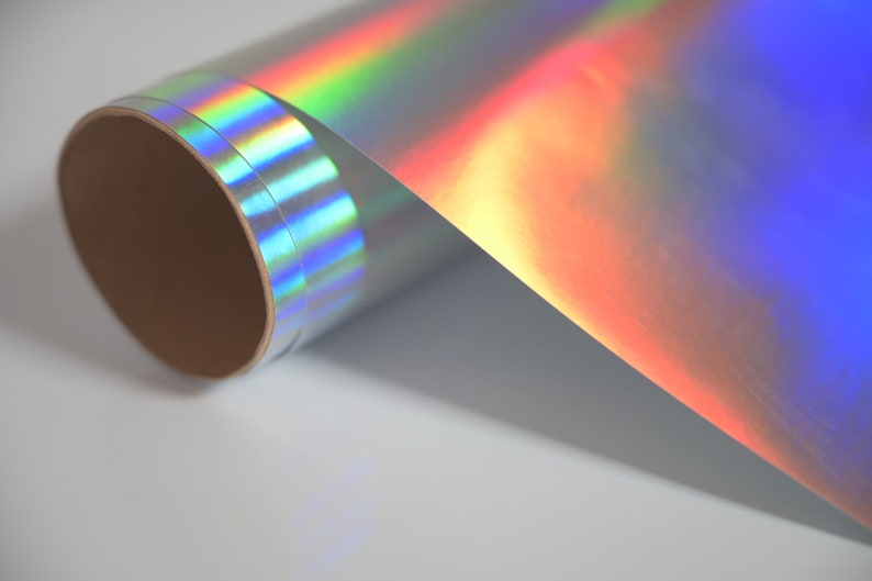 May include: A roll of iridescent holographic vinyl with a rainbow sheen. The vinyl is rolled up on a cardboard core.