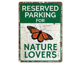 May include: A green and white metal sign with the text "Reserved Parking For Nature Lovers". A monarch butterfly is in the center of the sign.