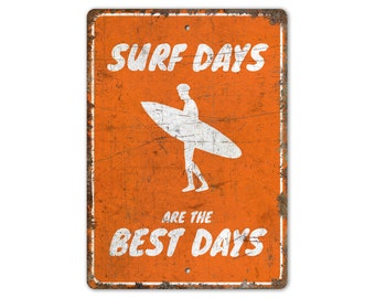 May include: Orange metal sign with a distressed look. The sign features a white silhouette of a surfer holding a surfboard. The text on the sign reads "Surf Days Are The Best Days".