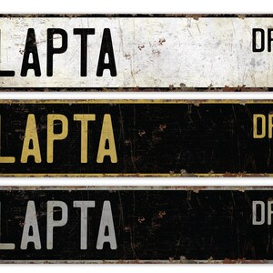 May include: Three vintage-style metal signs with the text "LAPTA DR" in black, gold, and silver lettering on a white, black, and black background, respectively.