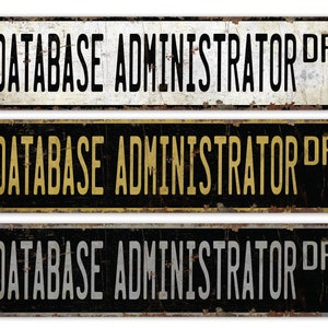 May include: Three vintage-style metal signs with the text "DATABASE ADMINISTRATOR DR" in black, gold, and silver lettering on a white, black, and black background, respectively.