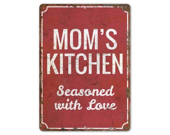 May include: Red metal sign with white text that reads "Mom's Kitchen Seasoned with Love".