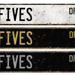 May include: Three vintage-style metal street signs. The signs are rectangular with rounded corners and the word "FIVES" in bold, black letters. The signs are in white, black, and black with yellow lettering, and all have "DR" in the corner.