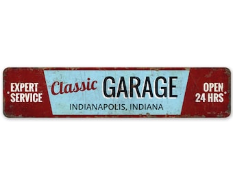 May include: A red and blue vintage-style metal sign with the text "Classic Garage" in black lettering. The sign also includes the text "Expert Service" and "Open 24 Hrs." and the location "Indianapolis, Indiana".