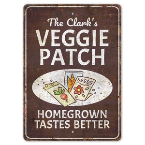Puede incluir: Un letrero de metal marrón con texto blanco que dice "The Clark's Veggie Patch Homegrown Tastes Better". El letrero presenta un óvalo blanco con una ilustración de paquetes de semillas y un rábano.