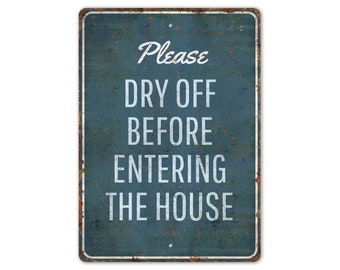 May include: A blue metal sign with white text that reads "Please Dry Off Before Entering The House". The sign has a distressed, rusty look.