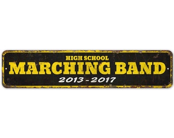 May include: A black and yellow metal sign with the text "HIGH SCHOOL MARCHING BAND 2013-2017".