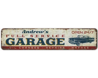 May include: A vintage-style metal sign with a distressed white background and red, white, and blue accents. The sign reads "Andrew's Full Service Garage" with the word "Garage" in large blue letters. The sign also includes the text "Open 24/7" and "Oil Changes, Repairs, Washes". A black and white illustration of a classic car is featured on the right side of the sign.