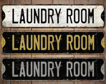 Op de afbeelding: Drie vintage-stijl metalen borden met de tekst "Laundry Room" in zwarte, gele en witte letters op een zwarte achtergrond. De borden hebben een verweerde, roestige uitstraling.