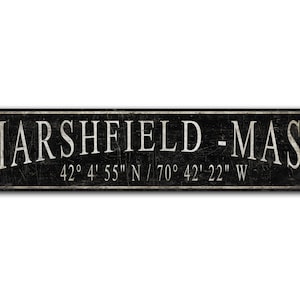 May include: Black and white sign with the text "MARSHFIELD - MASS" and the coordinates "42° 4' 55" N/70° 42' 22" W".