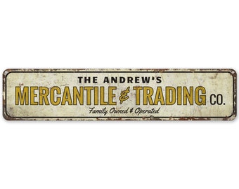 Op de afbeelding: Een vintage metalen bord met een witte achtergrond en gele tekst. Het bord staat er "The Andrew's Mercantile & Trading Co. Family Owned & Operated."