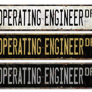 May include: Three vintage-style metal signs with the text "OPERATING ENGINEER DR" in black, gold, and silver lettering on a black background.
